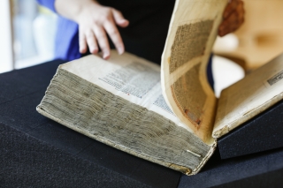 A close up of a large, old library book that someone is flipping the page