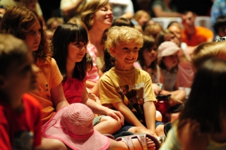 A group of children are sitting down and smiling